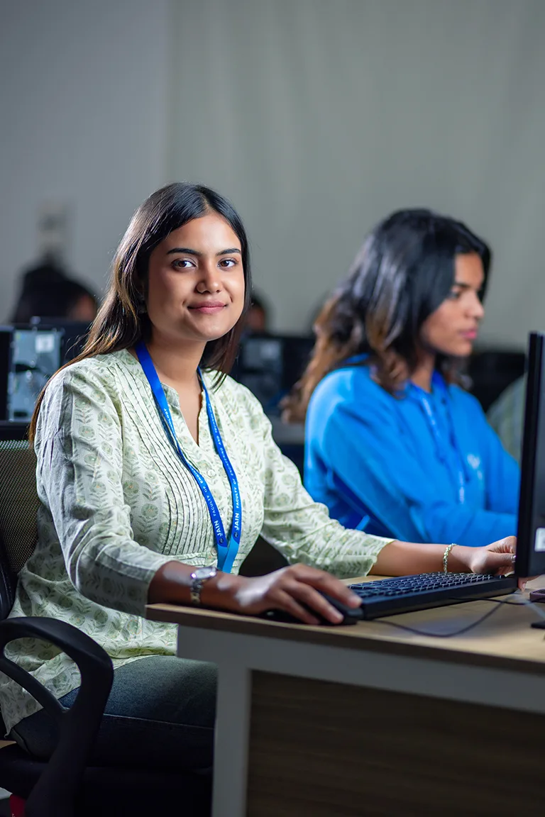A student smiles while using a computer in a lab, representing BTech Aerospace Engineering Colleges in Bangalore.