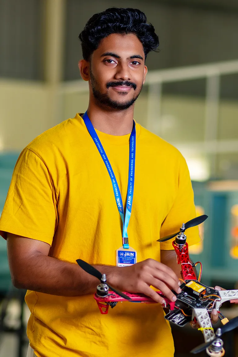 A student holds a drone proudly, representing MTech Structural Engineering Colleges in Bangalore.