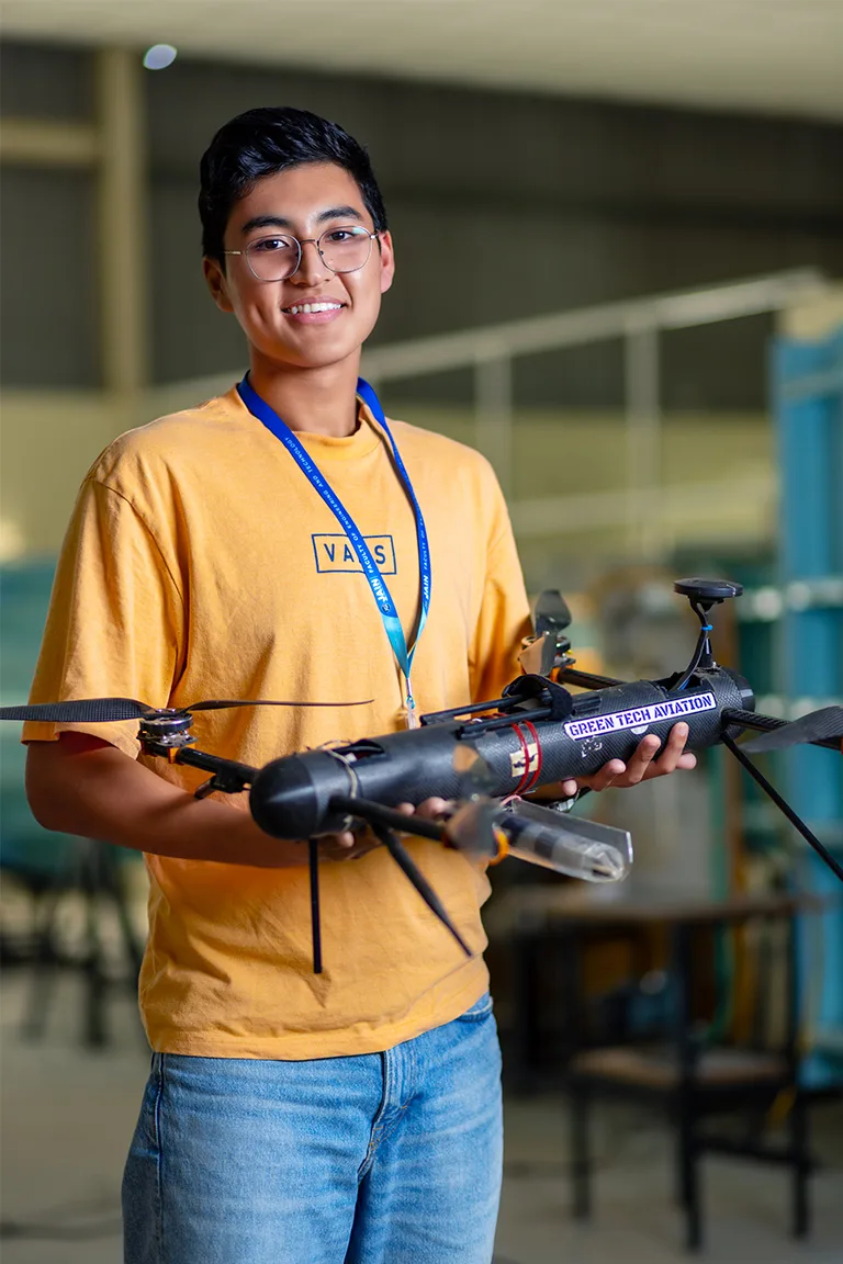 A student holds a drone, smiling, representing MTech Aerodynamics Engineering Colleges in Bangalore.