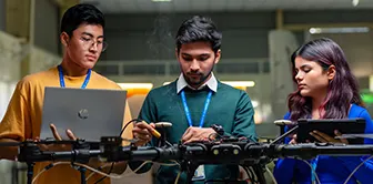 Aerospace engineering students in Bangalore working on drone technology with laptops nearby.
