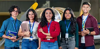 Students from one of the best colleges for aerospace engineering pose with a model aircraft behind.
